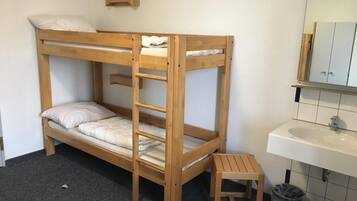 A bunk bed with a wooden ladder, a small wooden stool, a white sink, and a mirror above the sink.