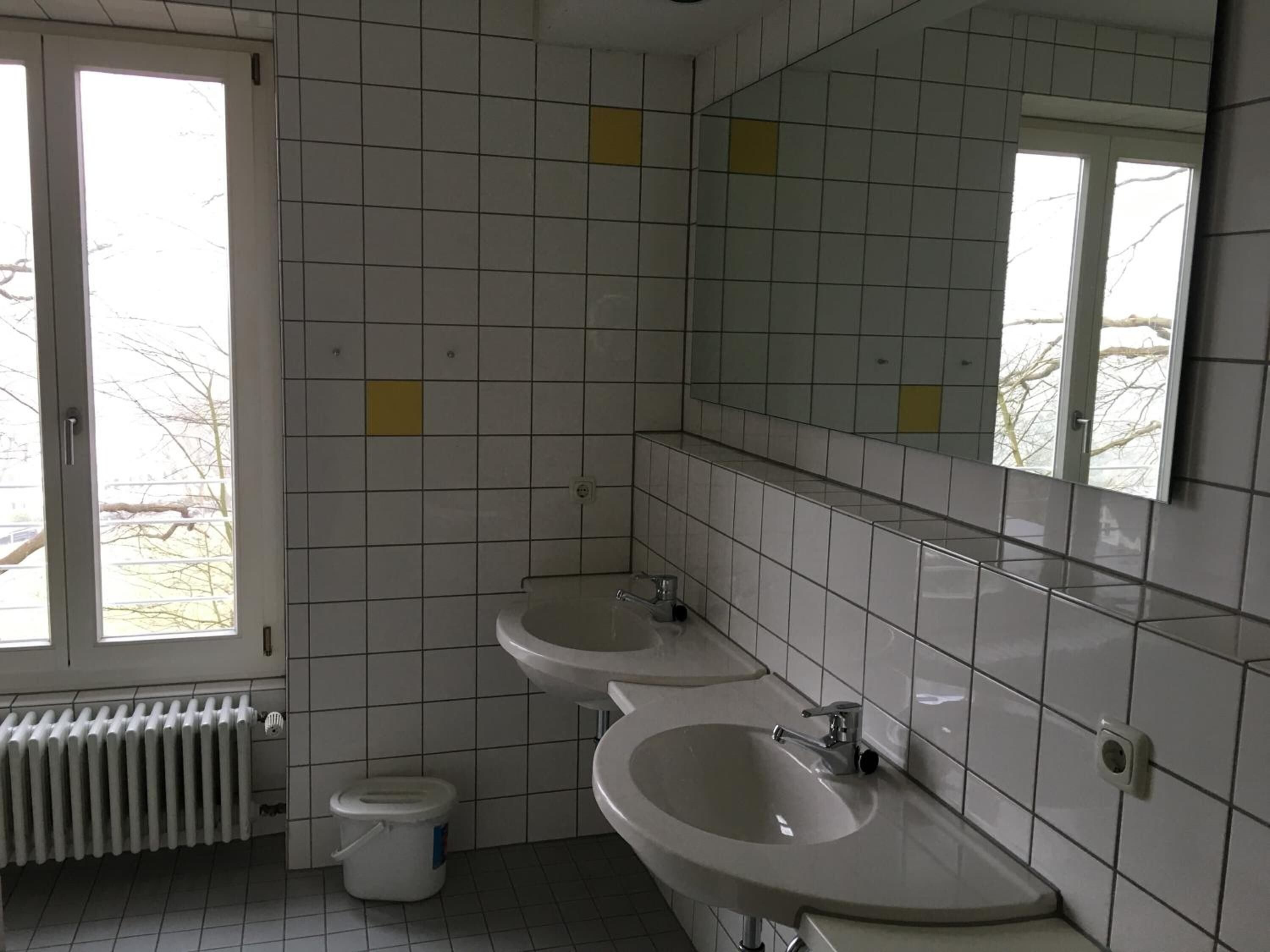 Ein Badezimmer mit zwei Waschbecken, einer Toilette und einem Heizkörper.