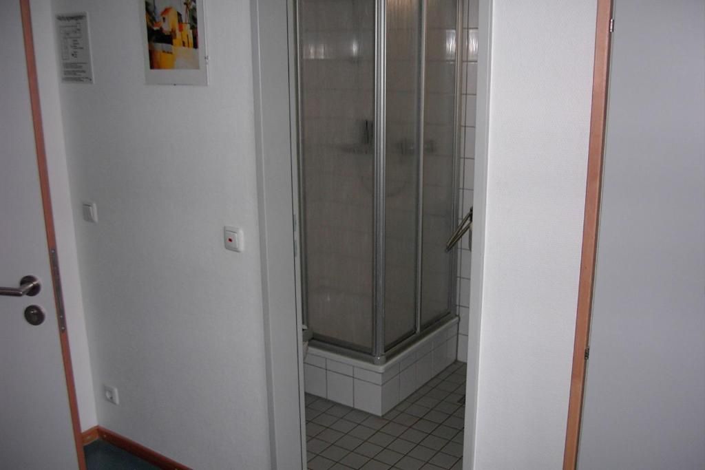 A hallway leading to a glass-enclosed shower area with tiled flooring.
