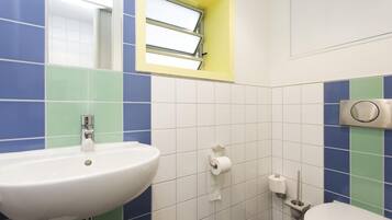 A bathroom with a white sink, a toilet, and a window with a yellow frame.