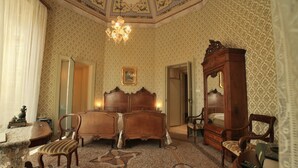 Une pièce comprenant un grand lit, deux chaises, une armoire en bois et un tapis à motifs.