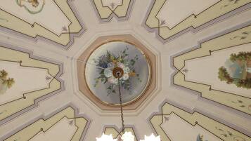 A ceiling with intricate floral and geometric patterns, a central floral chandelier, and a domed ceiling design.