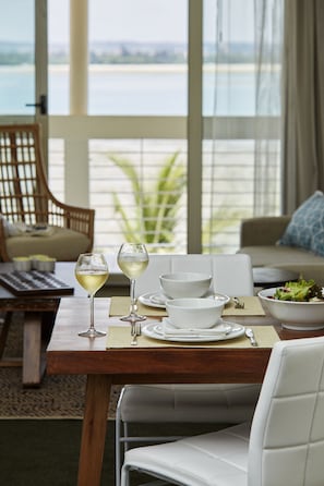 A dining table set with white plates, bowls, and glasses, overlooking a scenic view.