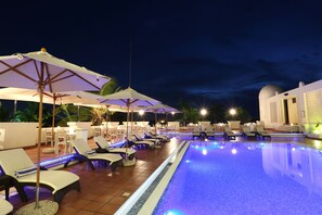 A poolside area with lounge chairs and umbrellas, a swimming pool, and a building with a dome and lattice work. - Hotel Slipway (Dar es Salaam)