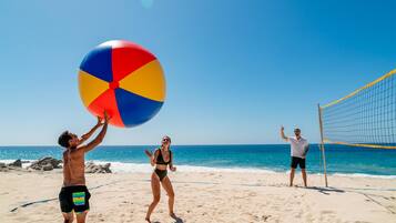 Partido de voleibol de playa con jugadores en traje de baño y una red.