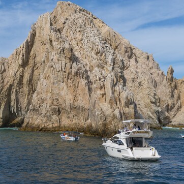 A boat near a large rock formation with an arch.