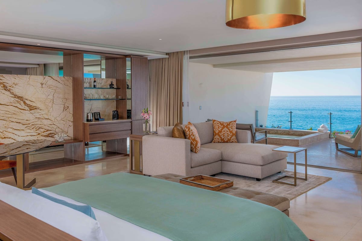 Una sala de estar moderna con sofá, mesa de centro y vista al mar.