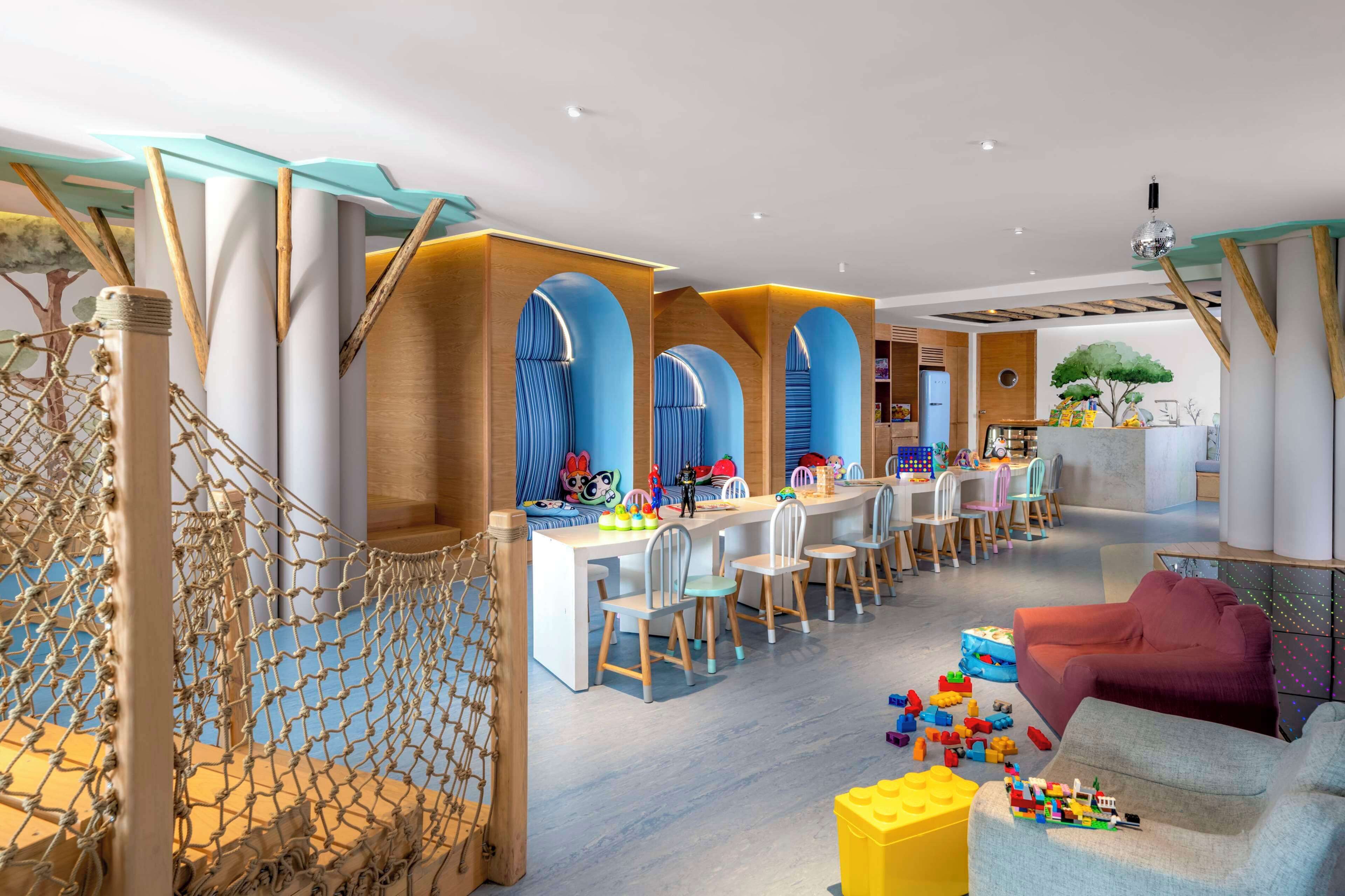 A modern children's play area with a long table, chairs, and a playpen.