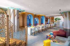 A modern children's play area with a long table, chairs, and a playpen.