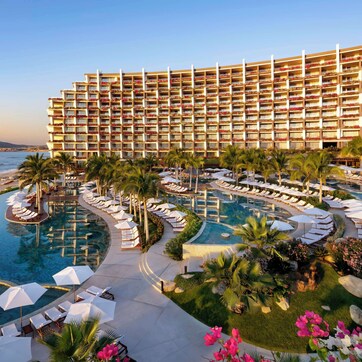 A hotel with multiple balconies, a swimming pool, and a beach view.