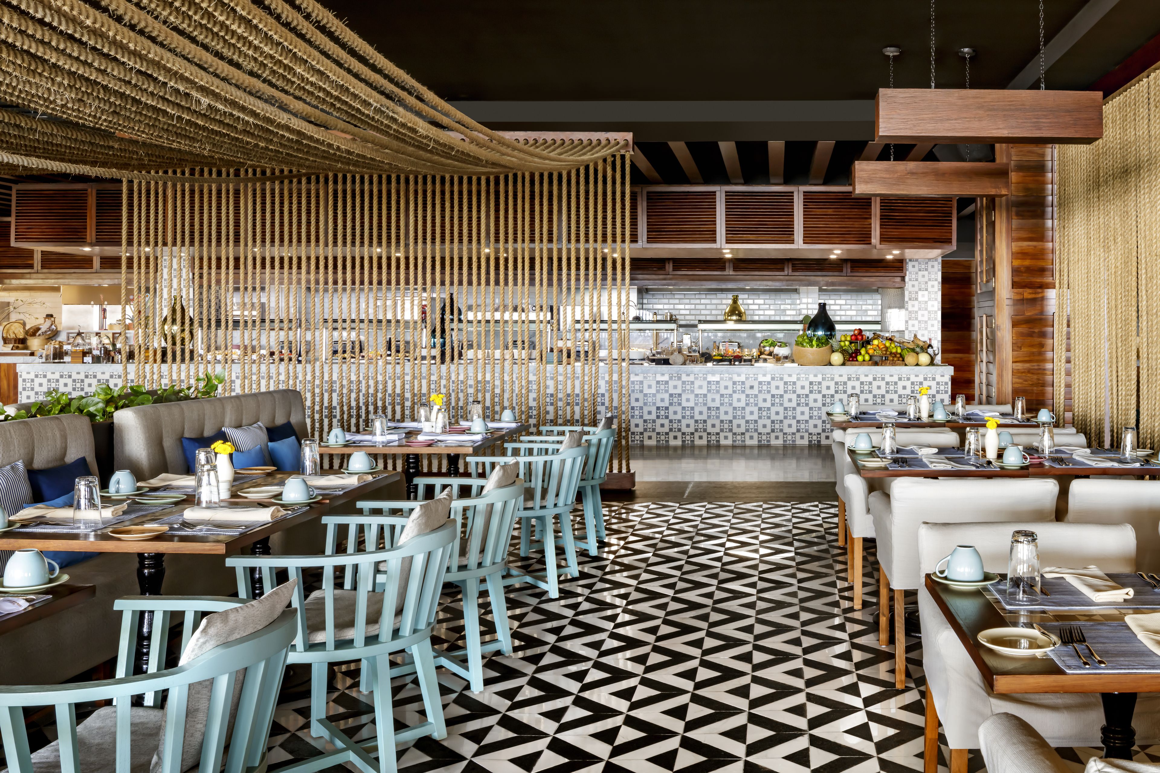 Un restaurante con piso de diseño geométrico, sillas azul claro y una zona de bar central con salpicadero de azulejos.