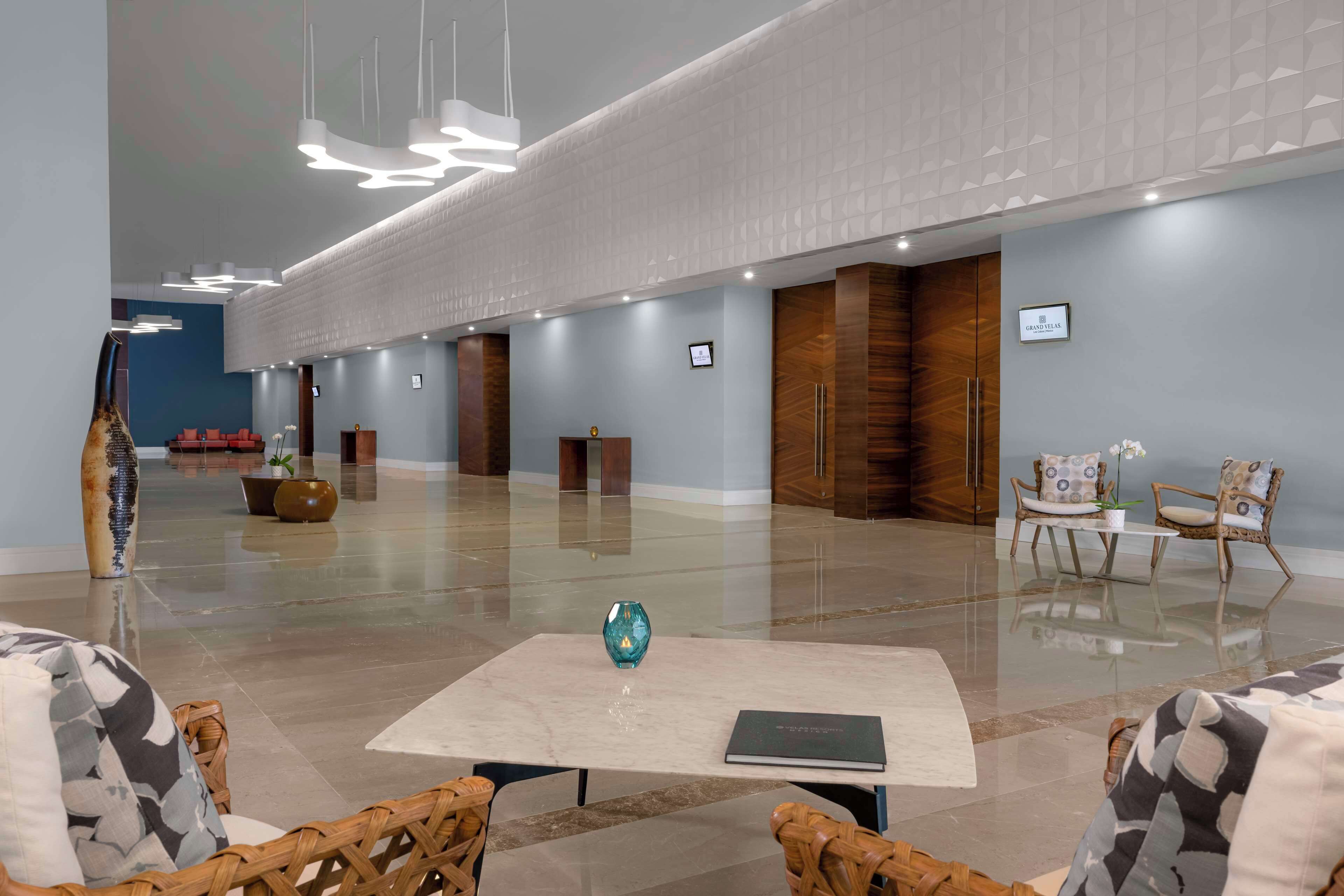 Eine geräumige Lobby mit einer Rezeption, einer Sitzecke und einer großen Vase auf einem Tisch.