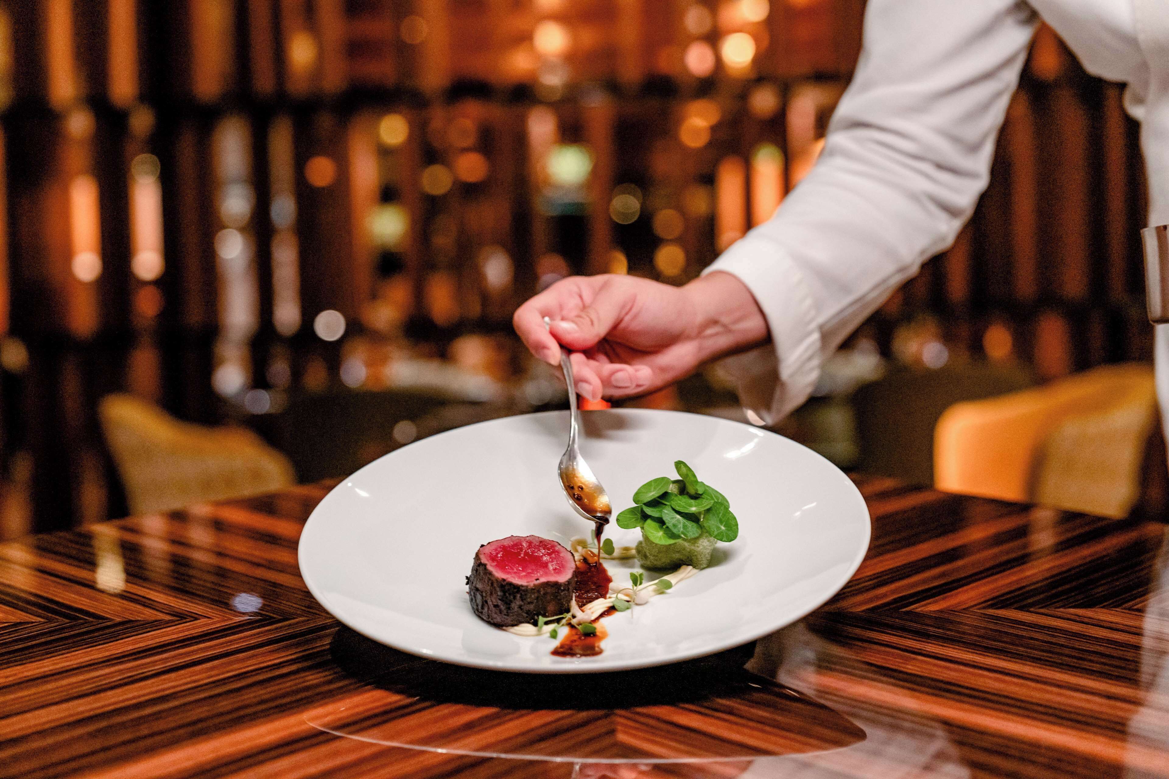 Un chef preparando un plato sobre una mesa de madera.
