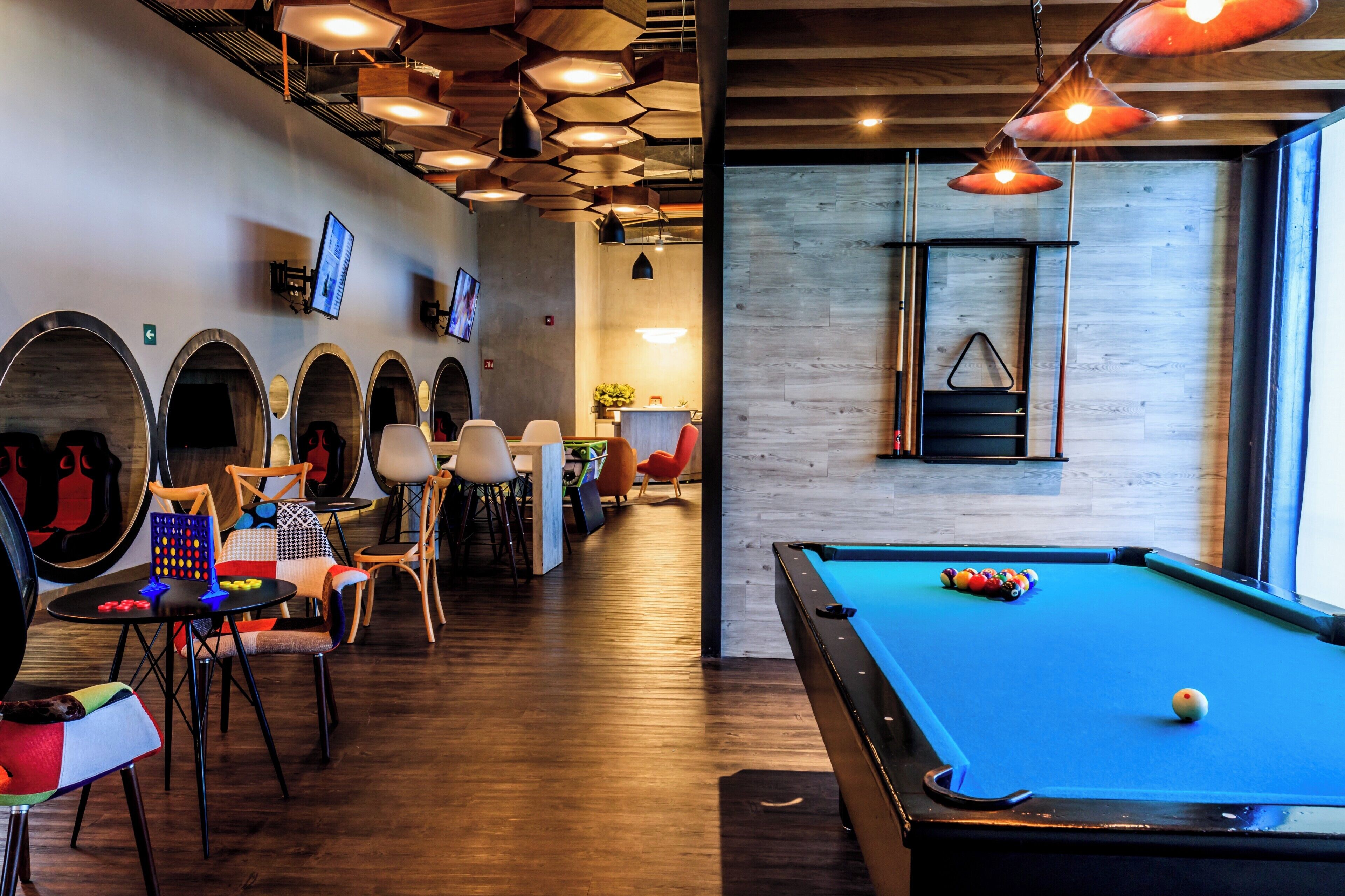 A billiards room with a pool table, multiple seating areas, and a wooden floor.