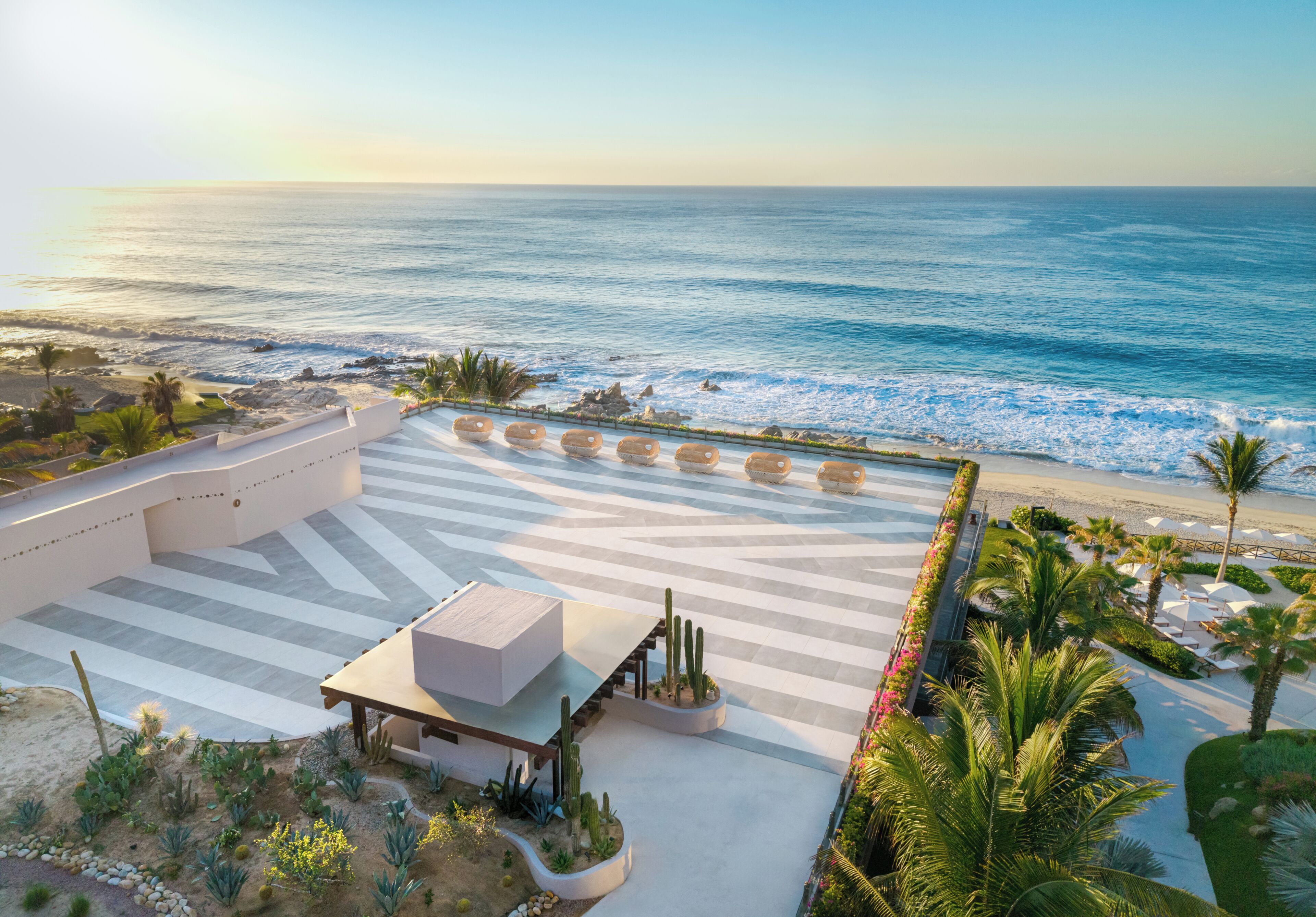A resort with a pool area, a cactus garden, and a view of the ocean.