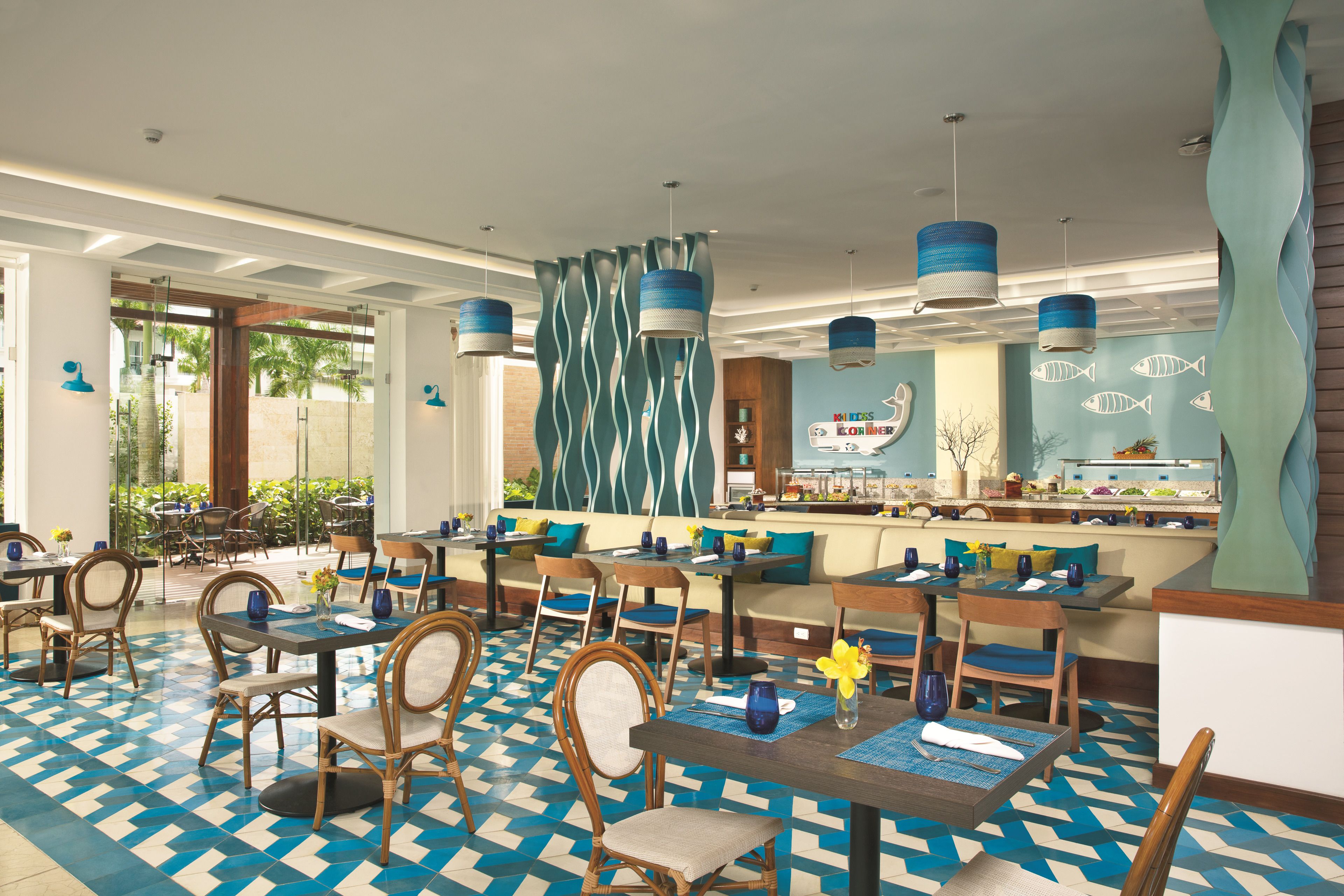 Un restaurante con suelo a cuadros, sillas de madera, decoración azul y blanca, y lámparas azules colgantes.