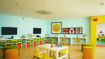 Un cuarto de juegos infantil lleno de color, con una mesa blanca, sillas amarillas y unidades de almacenaje coloridas.