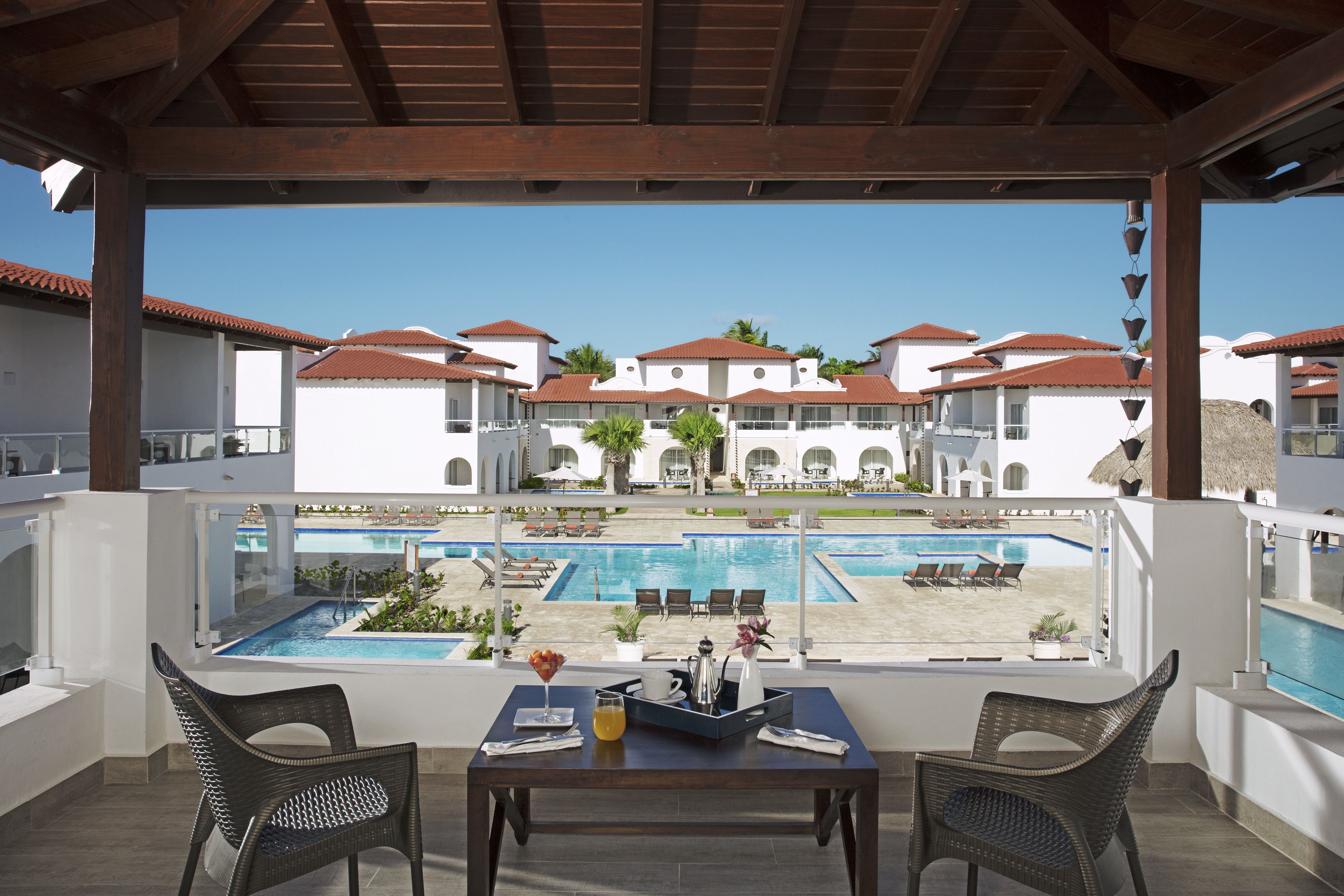 Ein Balkon mit Tisch und Stühlen mit Blick auf einen Pool und Hotelgebäude.