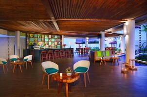 Un vestíbulo amplio con suelo de madera, zona de bar y diferentes distribuciones de asientos.