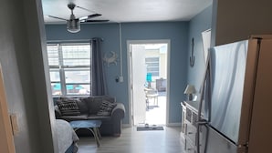 A compact kitchen with a refrigerator, wooden flooring, and a dining area with a table and chairs. - Ashley Brooke Beach Resort (Deerfield Beach)