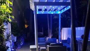 An outdoor patio area with seating and a pergola covered with string lights. - Ashley Brooke Beach Resort (Deerfield Beach)
