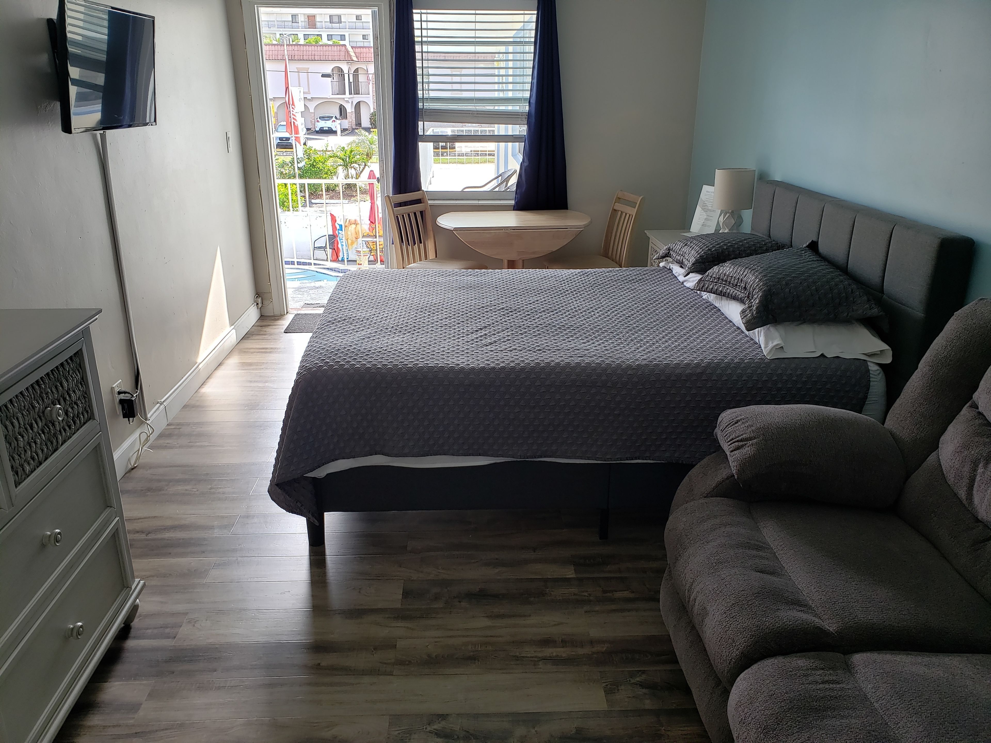 Une chambre à coucher comprenant un lit, un canapé, une télévision, un bureau et une fenêtre donnant sur l’extérieur.