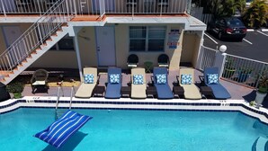 A pool area with lounge chairs and a staircase leading to an upper level. - Ashley Brooke Beach Resort (Deerfield Beach)