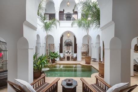 A courtyard with a pool, seating areas, and potted plants.