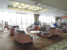 Un amplio salón con diversas opciones de asientos, un televisor y una estación de café.