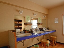 Un baño con un mueble largo, dos lavamanos, un espejo y una repisa con cestas.