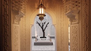 An ornate hallway with intricate wall carvings, a central tree sculpture, and a hanging lantern. - Riad Kheirredine (Marrakech)