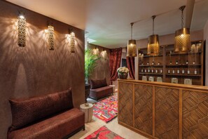 A modern interior with a sofa, patterned cushions, a patterned rug, and a wooden cabinet with bottles.