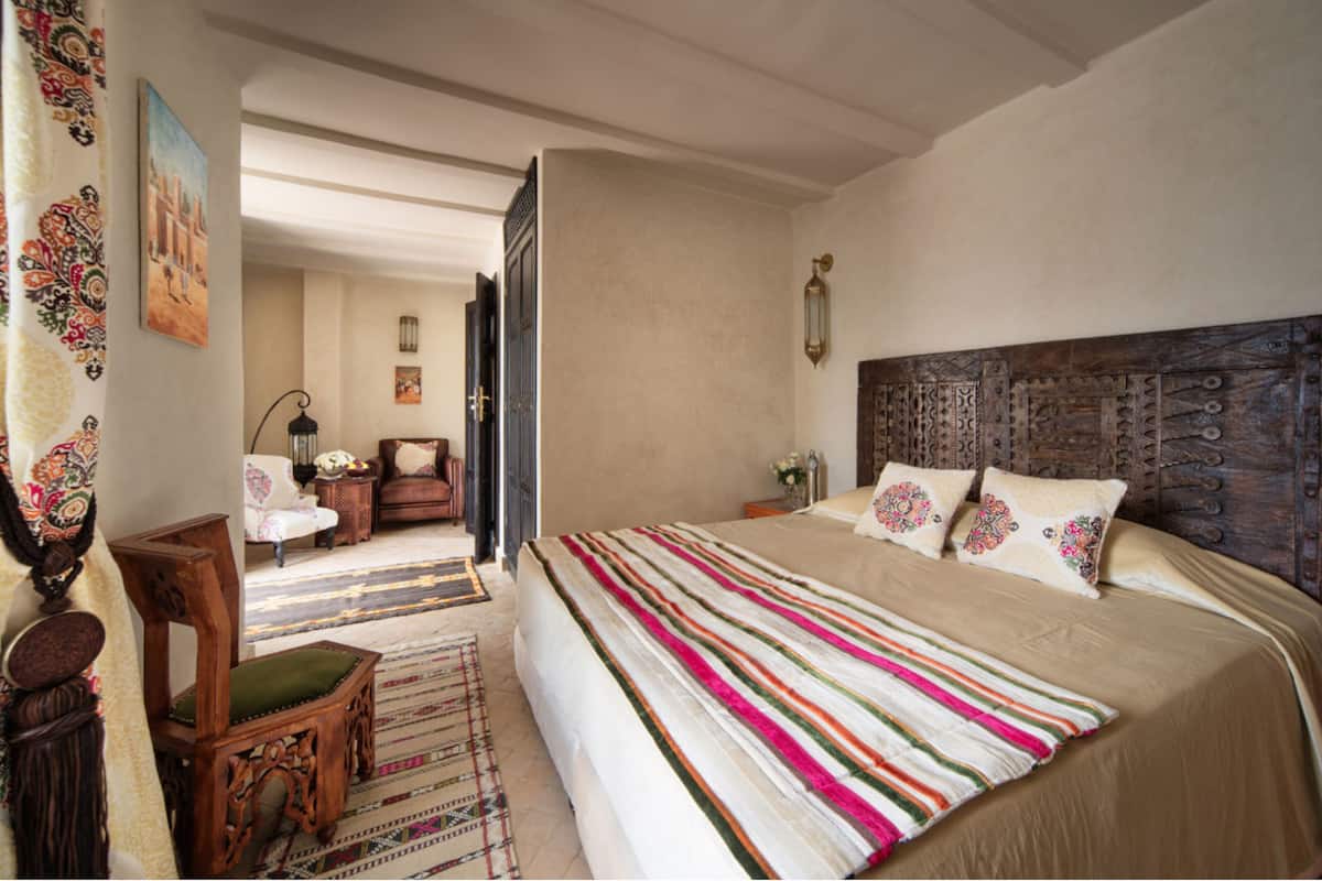 Un dormitorio amplio con una cama grande, un cabecero de madera y vistas a un pasillo con una silla y una mesa.