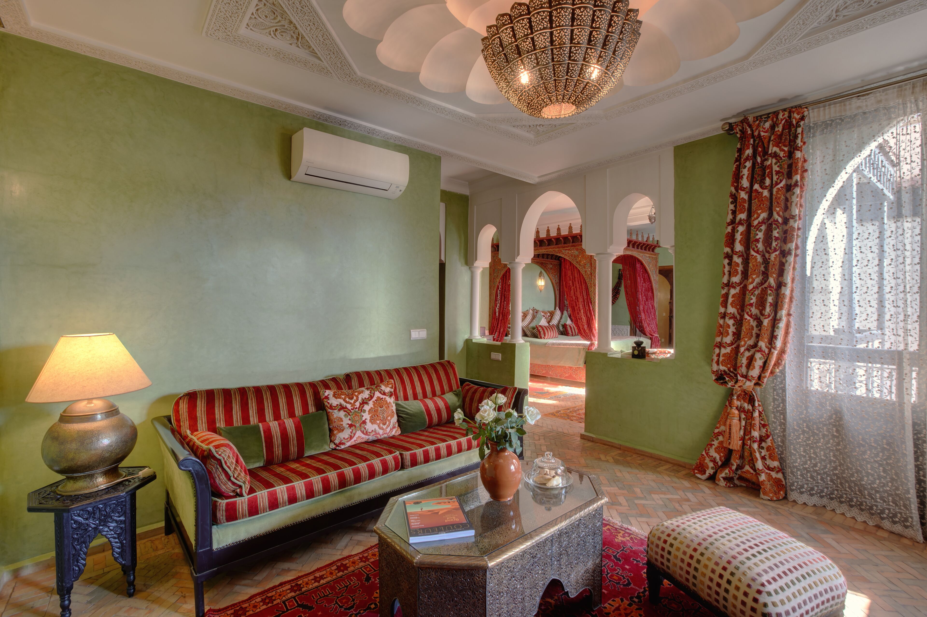 A living room with a sofa, a coffee table with a vase, a lamp, and a patterned rug.