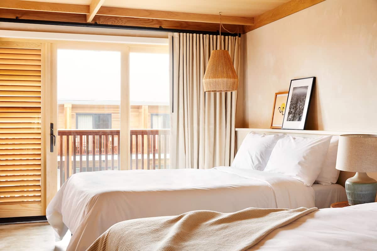 A bedroom with a bed, a hanging lamp, and a framed picture on the wall.