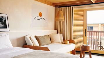Habitación de hotel con dos camas, un ventanal con persianas, una lámpara colgante y un cuadro en la pared.
