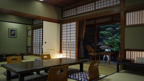 Una habitación japonesa tradicional con suelo de tatami, una mesita baja y puertas correderas.