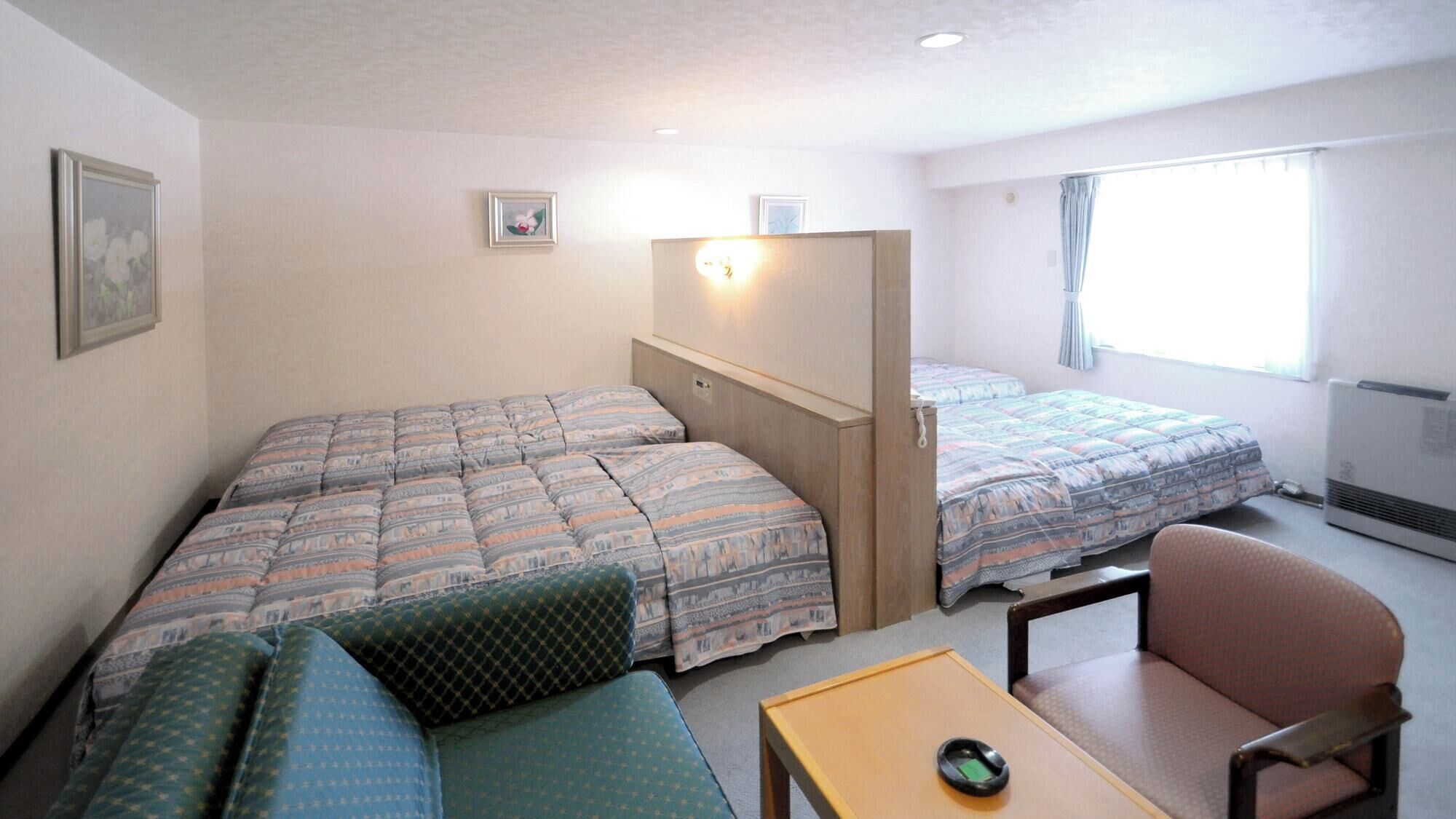 A small, well-lit room with two beds, a sofa, a chair, and a table.