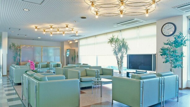 A modern waiting area with seating, a television, and large windows. - New Chiko Hotel (Hokkaido)