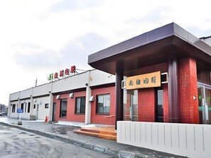 A building with a red brick facade, a flat roof, and a sign with Chinese characters. - New Chiko Hotel (Hokkaido)