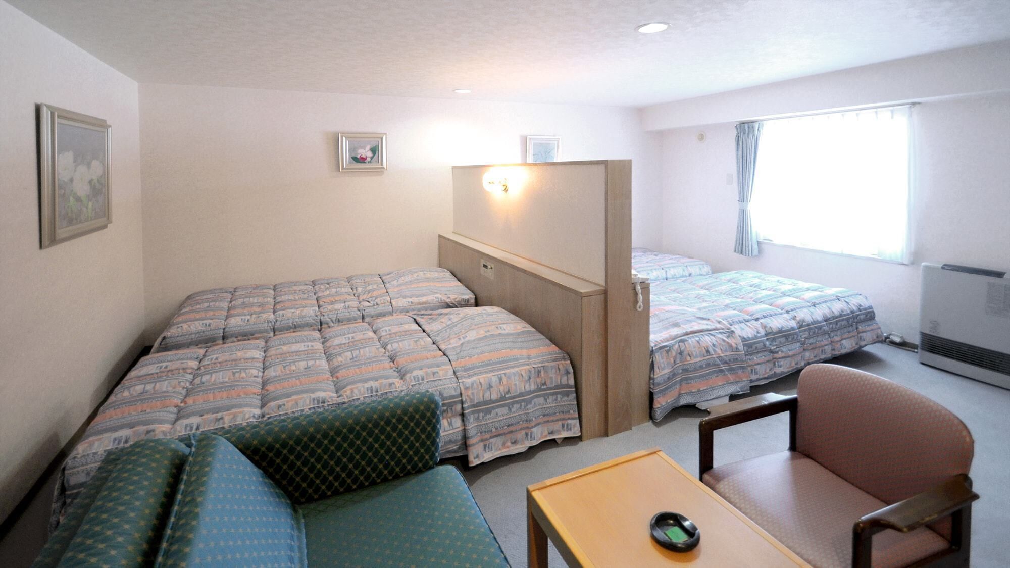 A small, well-lit room with two beds, a sofa, a chair, and a table.