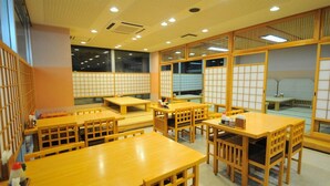 A traditional Japanese restaurant interior with tatami mat flooring, wooden tables and chairs, and shoji screens. - New Chiko Hotel (Hokkaido)