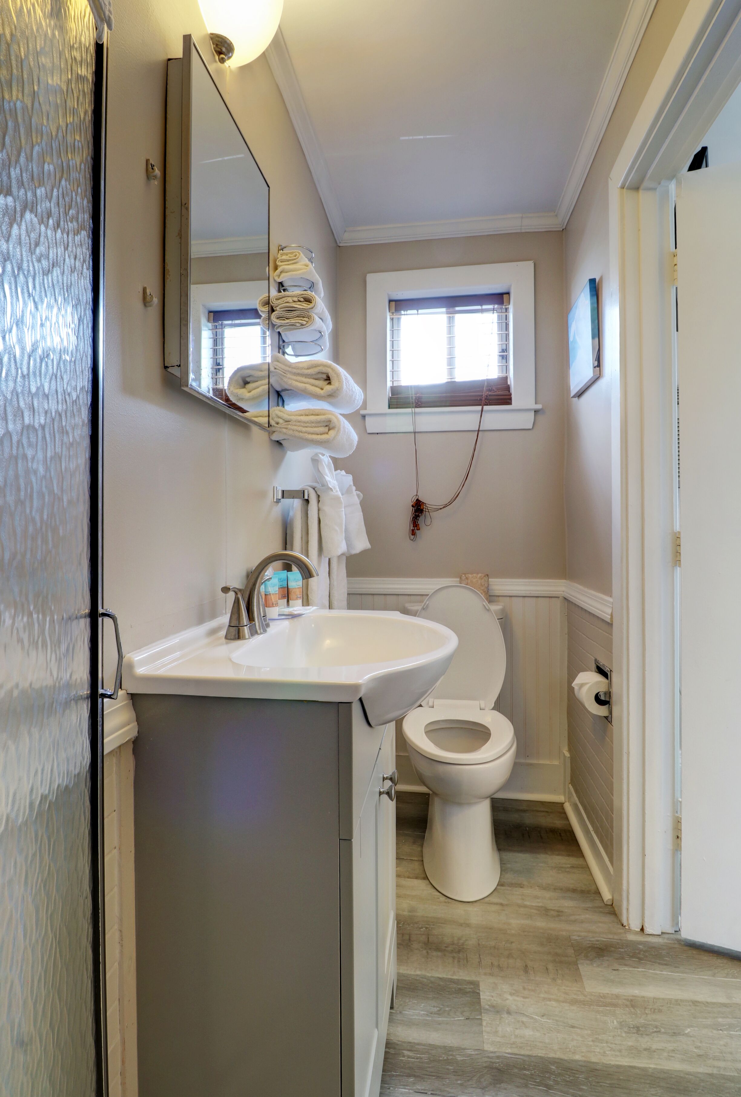 Ein Badezimmer mit Waschbecken, Toilette und einem Fenster über der Toilette.