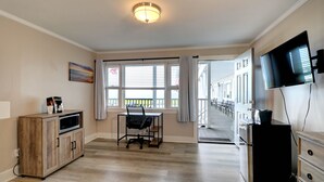 A modern kitchen with wooden cabinets, a microwave, a dining table with chairs, and a TV mounted on the wall. - On the Beach Motel (Old Orchard Beach)