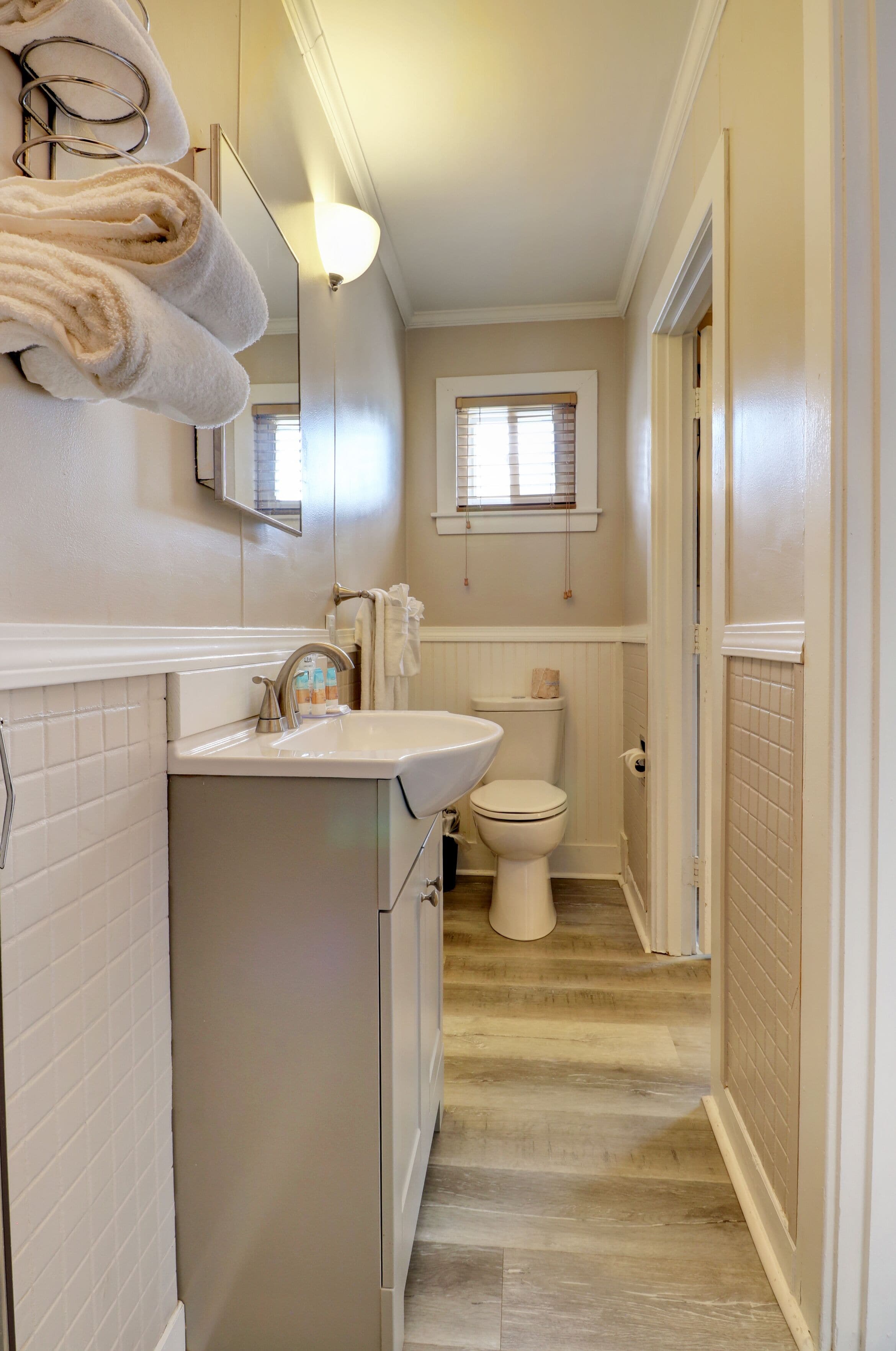 A narrow bathroom with a sink, mirror, and toilet.