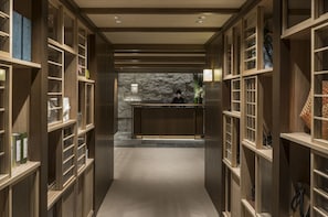 A reception area with wooden shelving, a reception desk, and a stone wall in the background.
