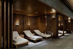 A spa area with wooden paneling, three lounge chairs, and a tiled floor.