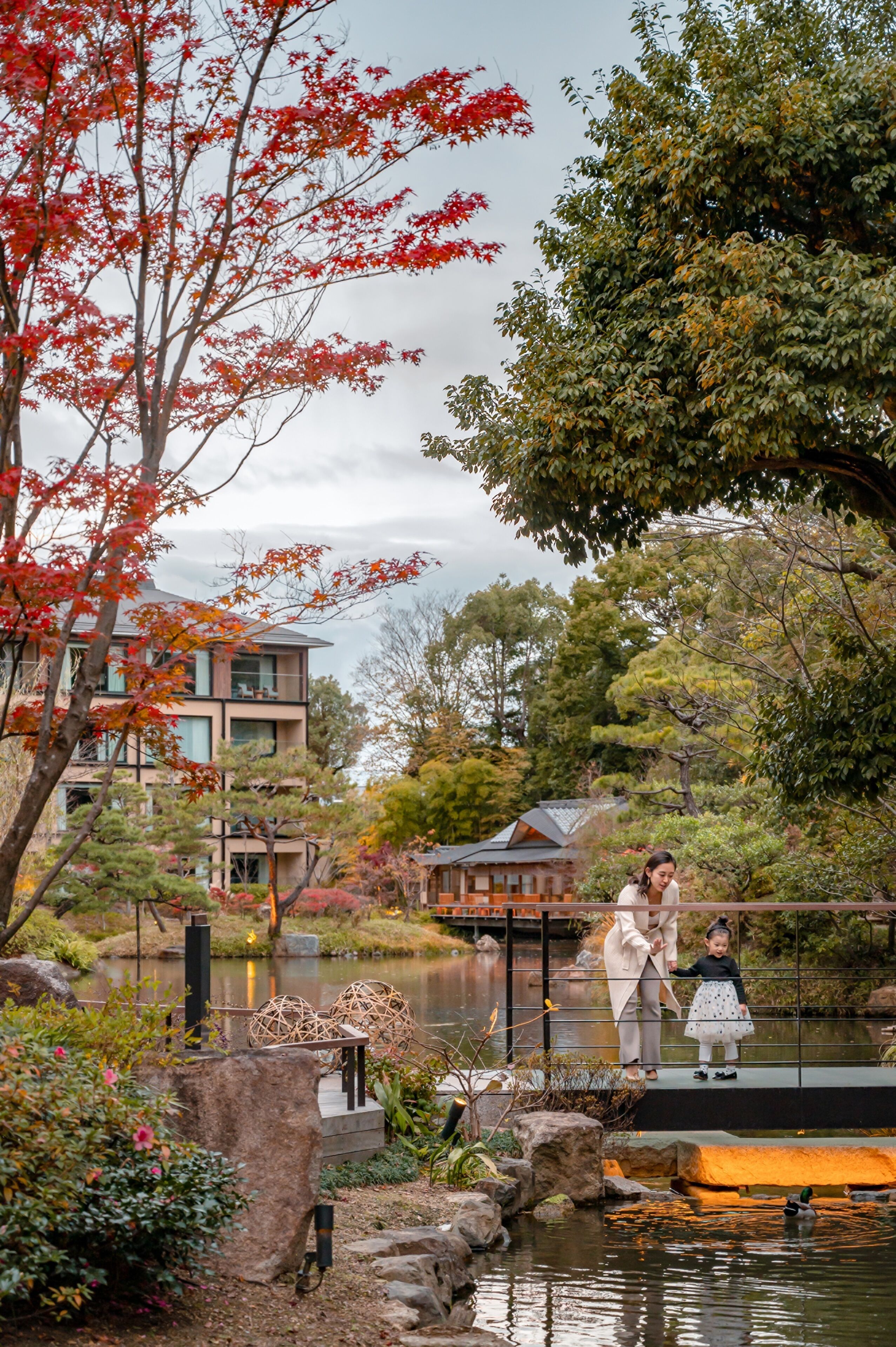 A traditional Japanese garden with a pond, stone lanterns, and a wooden bridge.