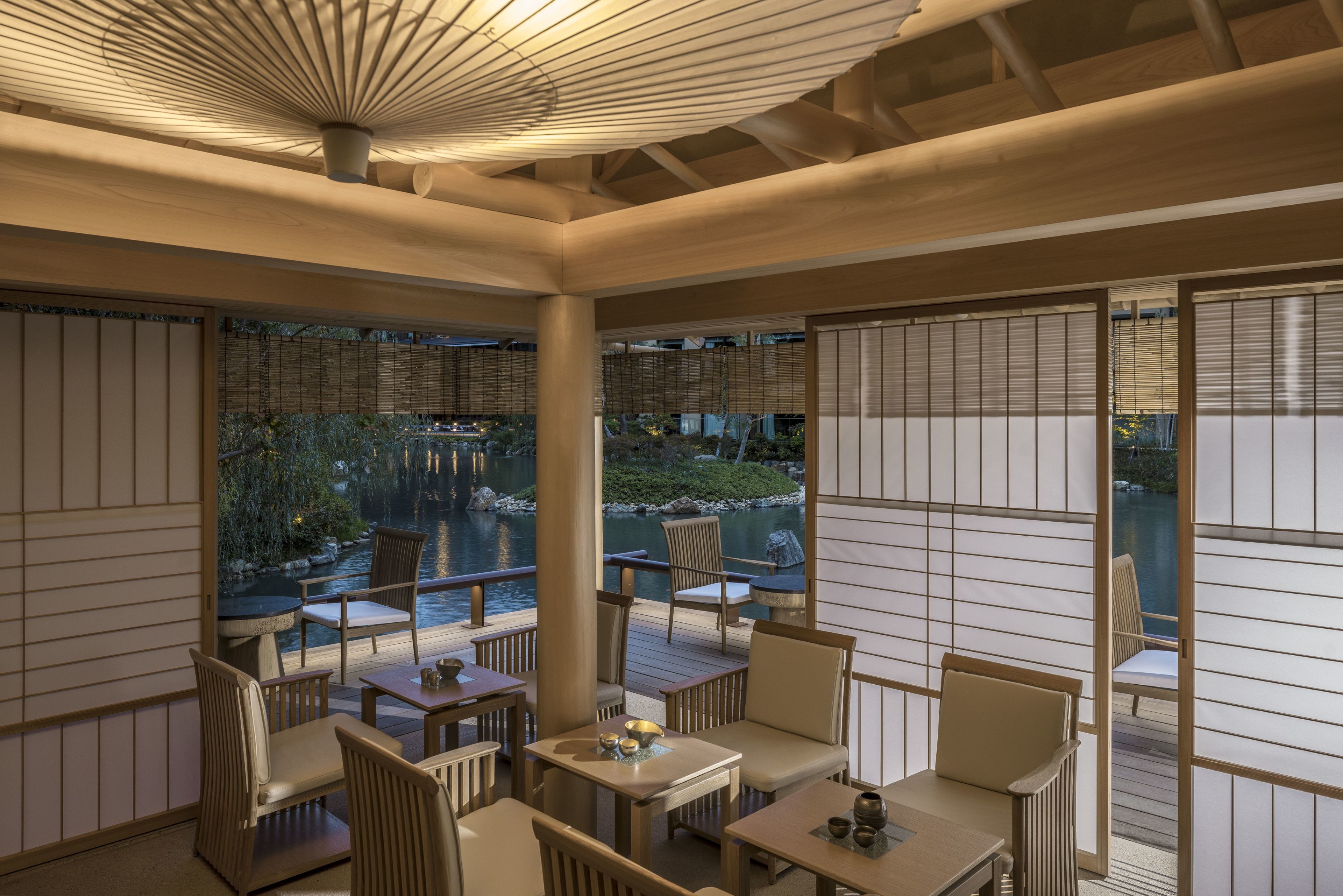 A serene indoor seating area with wooden furniture and a view of a pond.