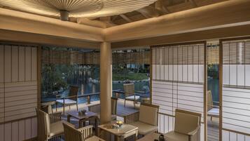 A serene indoor seating area with wooden furniture and a view of a pond.